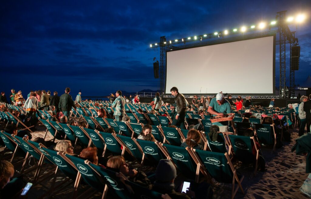 A crowd watching an outdoor film screening at dusk