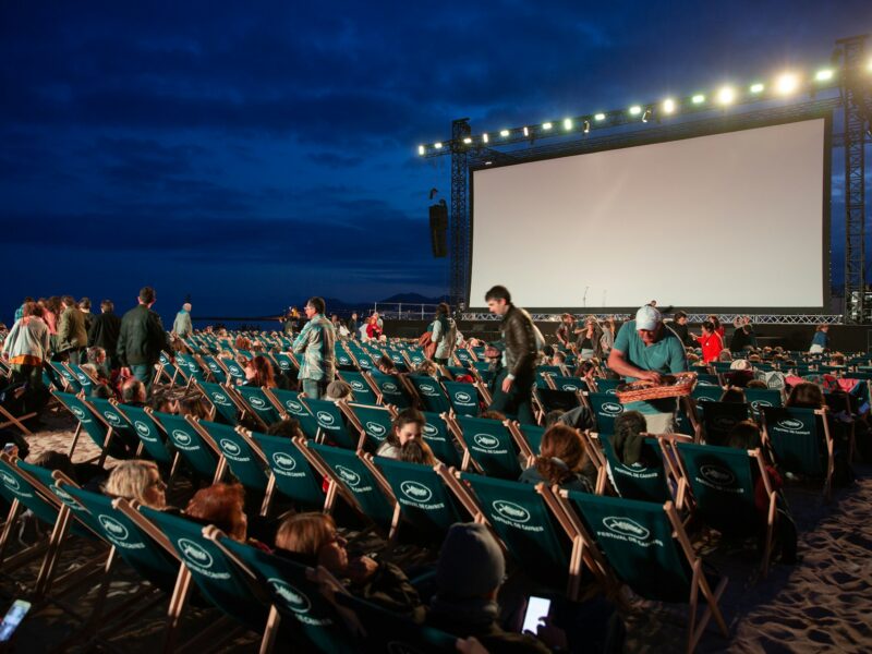 A crowd watching an outdoor film screening at dusk