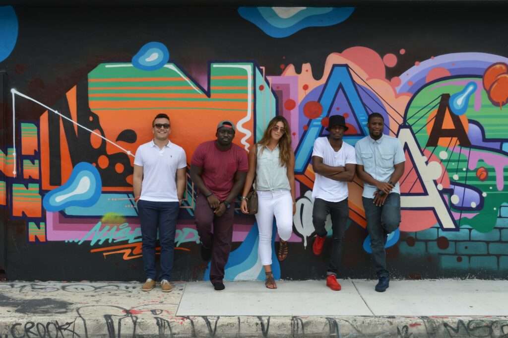 A group of young people in front of a colorful graffiti wall