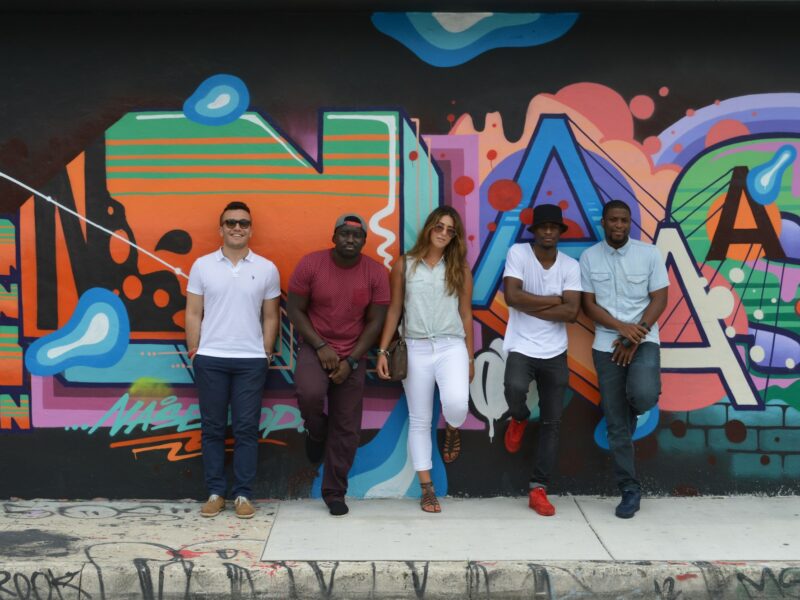 A group of young people in front of a colorful graffiti wall