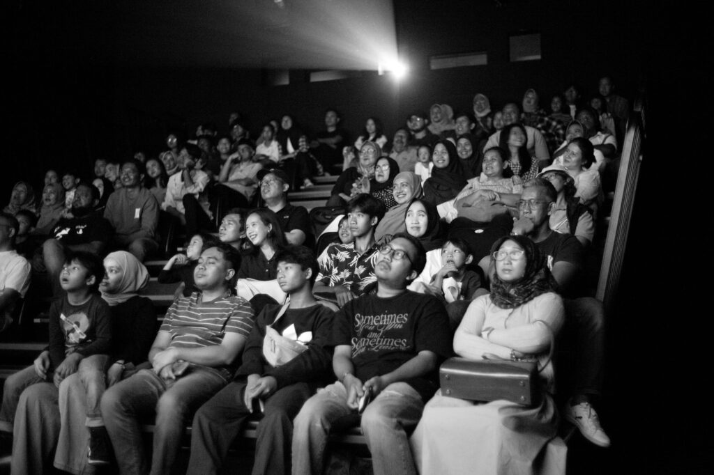 A full audience watching a film in a dark theater