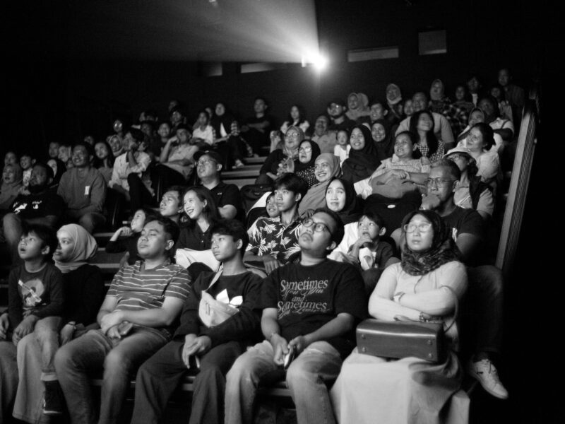 A full audience watching a film in a dark theater